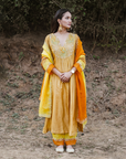 A woman wearing mustard colored Silk Kurta Set with Organza Dupatta.