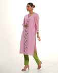A women wearing light pink colored kurta set with green colored pants.