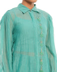 A women wearing full sleeves aqua colored shirt with shorts.