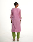 A women wearing light pink colored kurta set with green colored pants.