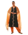 A women wearing black colored kurta set with orange colored pants and dupatta.