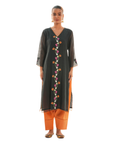 A women wearing black colored kurta set with orange colored pants.