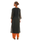 A women wearing black colored kurta set with orange colored pants.