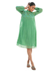 A women wearing green colored full sleeves designer dress with knee length.