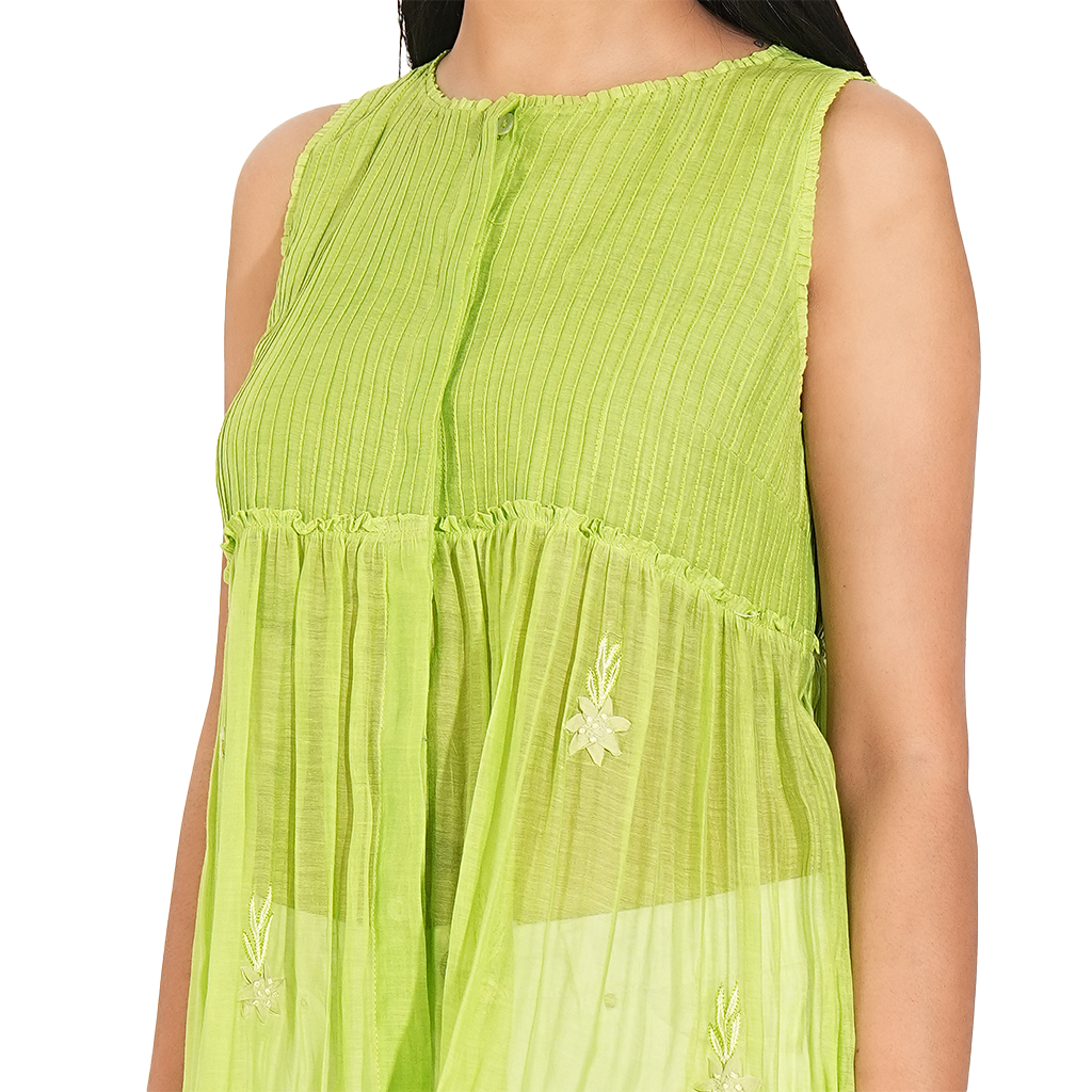 A women wearing parrot green colored designer sleeveless top with white pants.