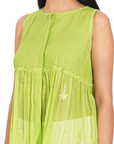 A women wearing parrot green colored designer sleeveless top with white pants.