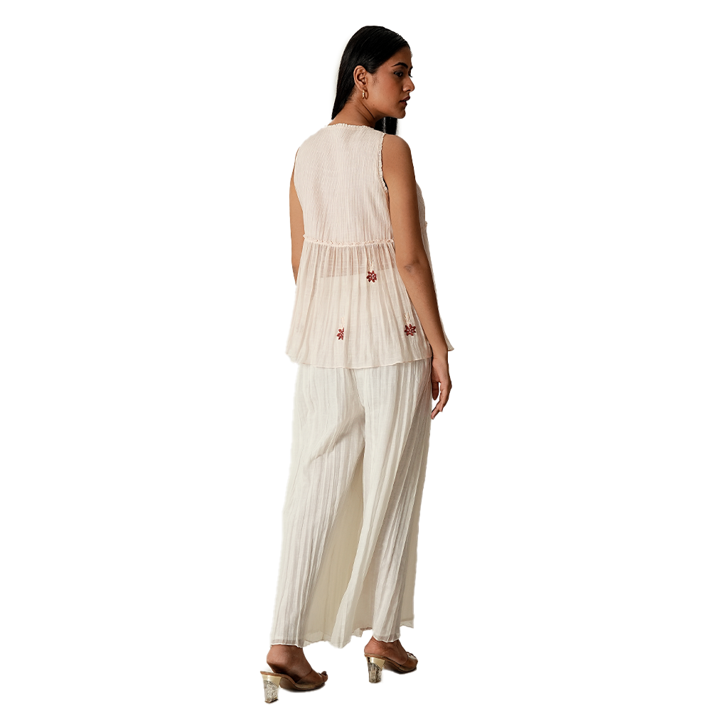 A women wearing pink salt colored designer sleeveless top with palazzo.