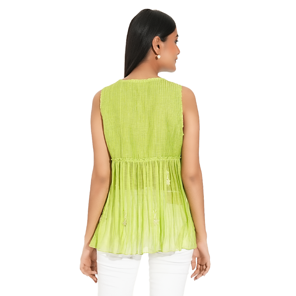 A women wearing parrot green colored designer sleeveless top with white pants.