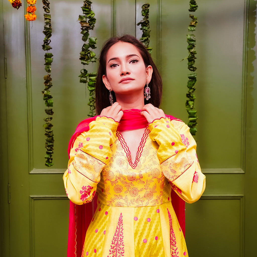 A women wearing yellow and pick Chanderi silk Anarkali kurta set with Pink Dupatta.