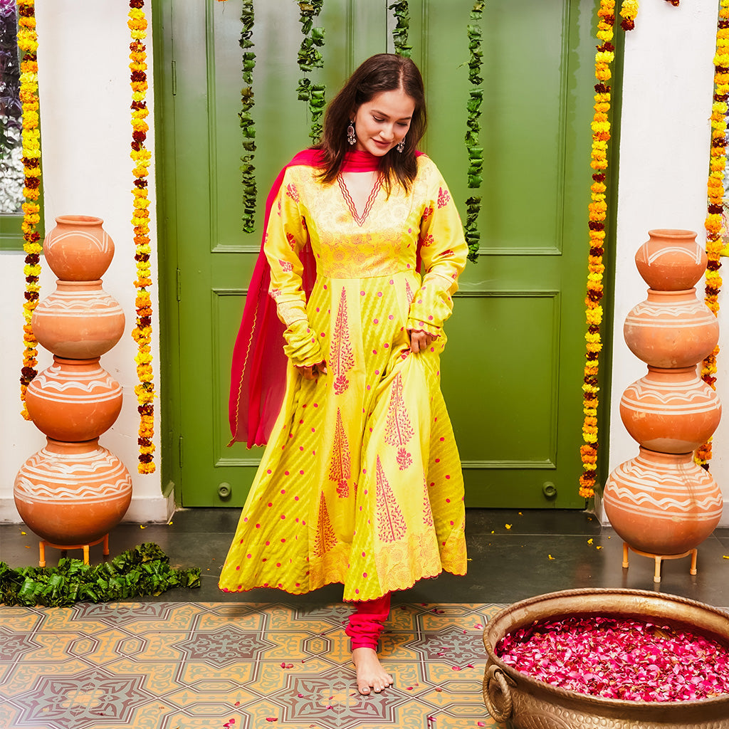 A women wearing yellow and pick Chanderi silk Anarkali kurta set with Pink Dupatta.