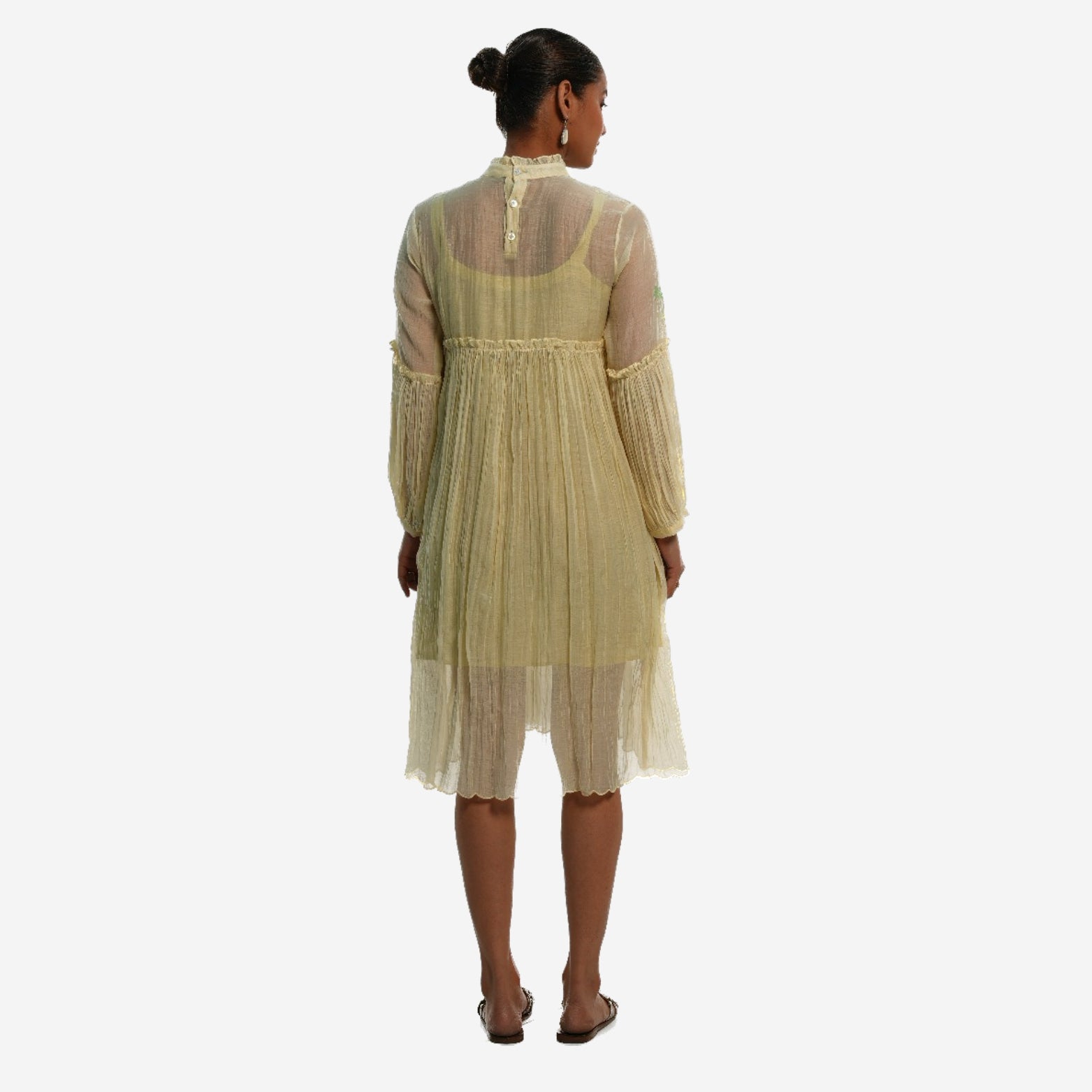 A women wearing white colored full sleeves designer dress with knee length.
