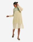 A women wearing white colored full sleeves designer dress with knee length.