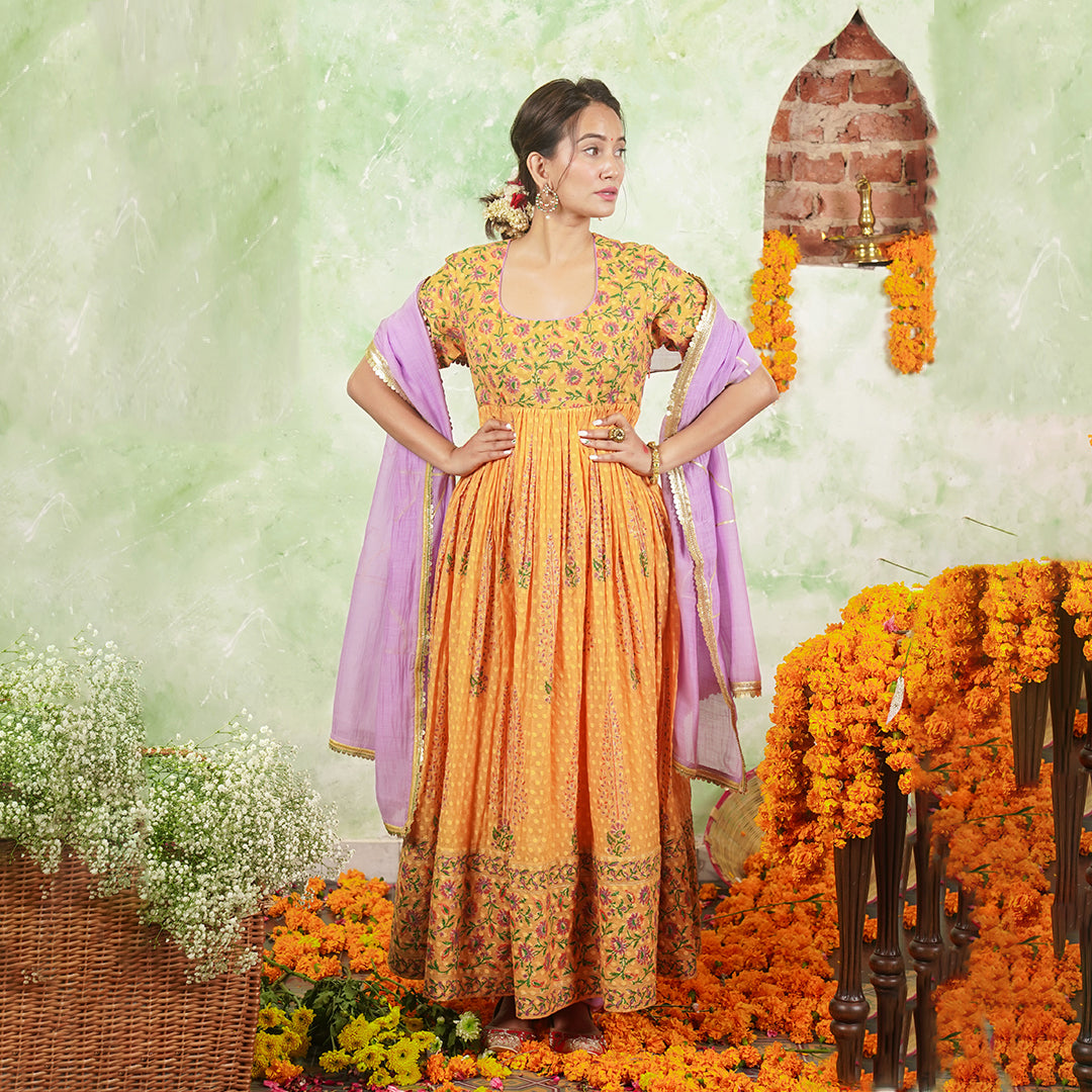 A women wearing Orange Anarkali Kurta Set with Purple Dupatta.