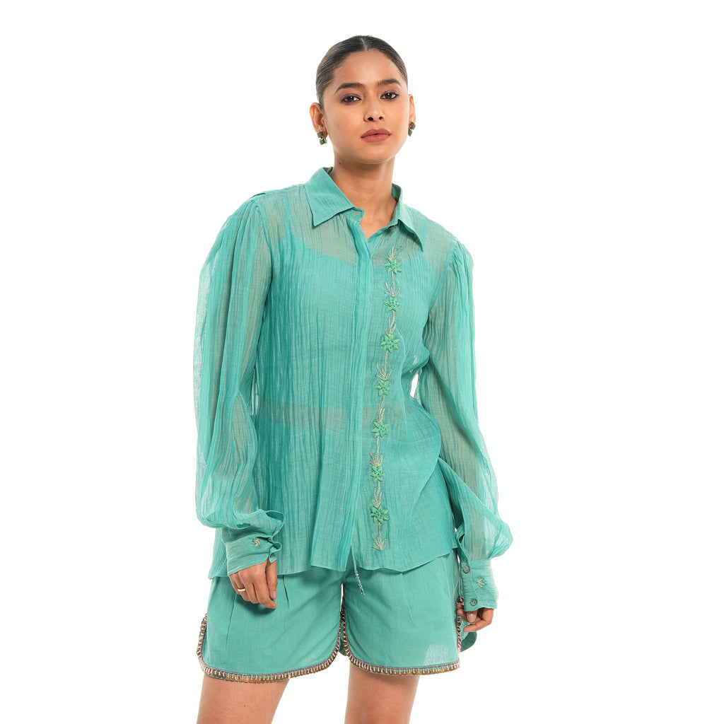 A women wearing full sleeves aqua colored shirt with shorts.