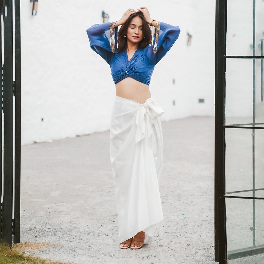 A woman wearing Blue Colored Blouse and White Drape Skirt Co-ord Set.