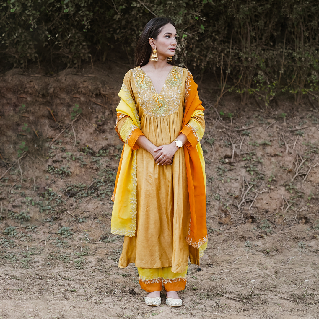 A woman wearing mustard colored Silk Kurta Set with Organza Dupatta.