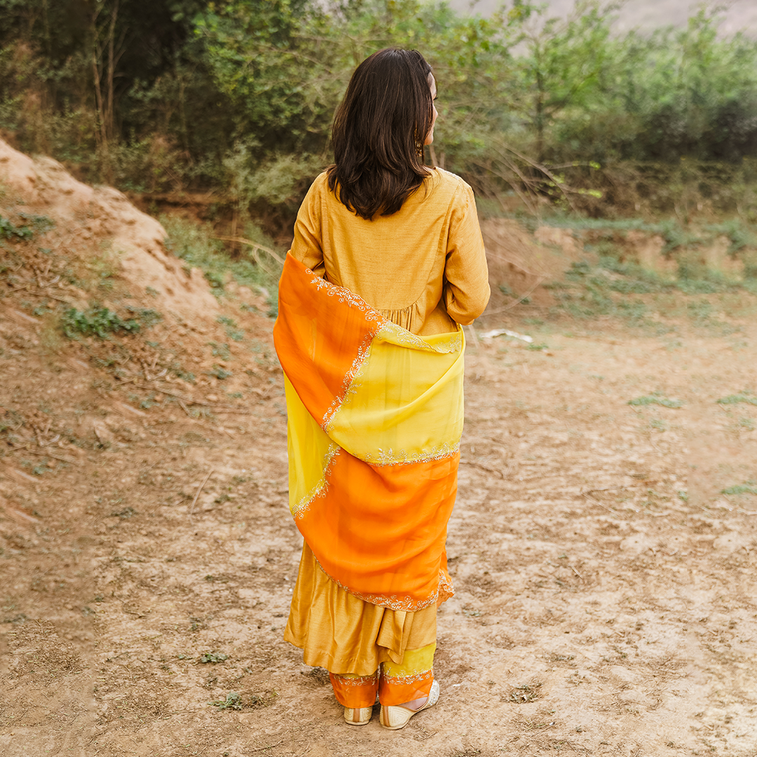 A woman wearing mustard colored Silk Kurta Set with Organza Dupatta.