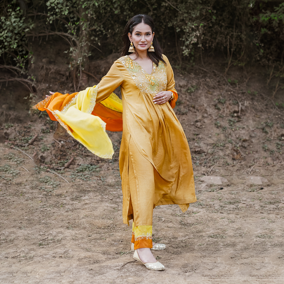 A woman wearing mustard colored Silk Kurta Set with Organza Dupatta.