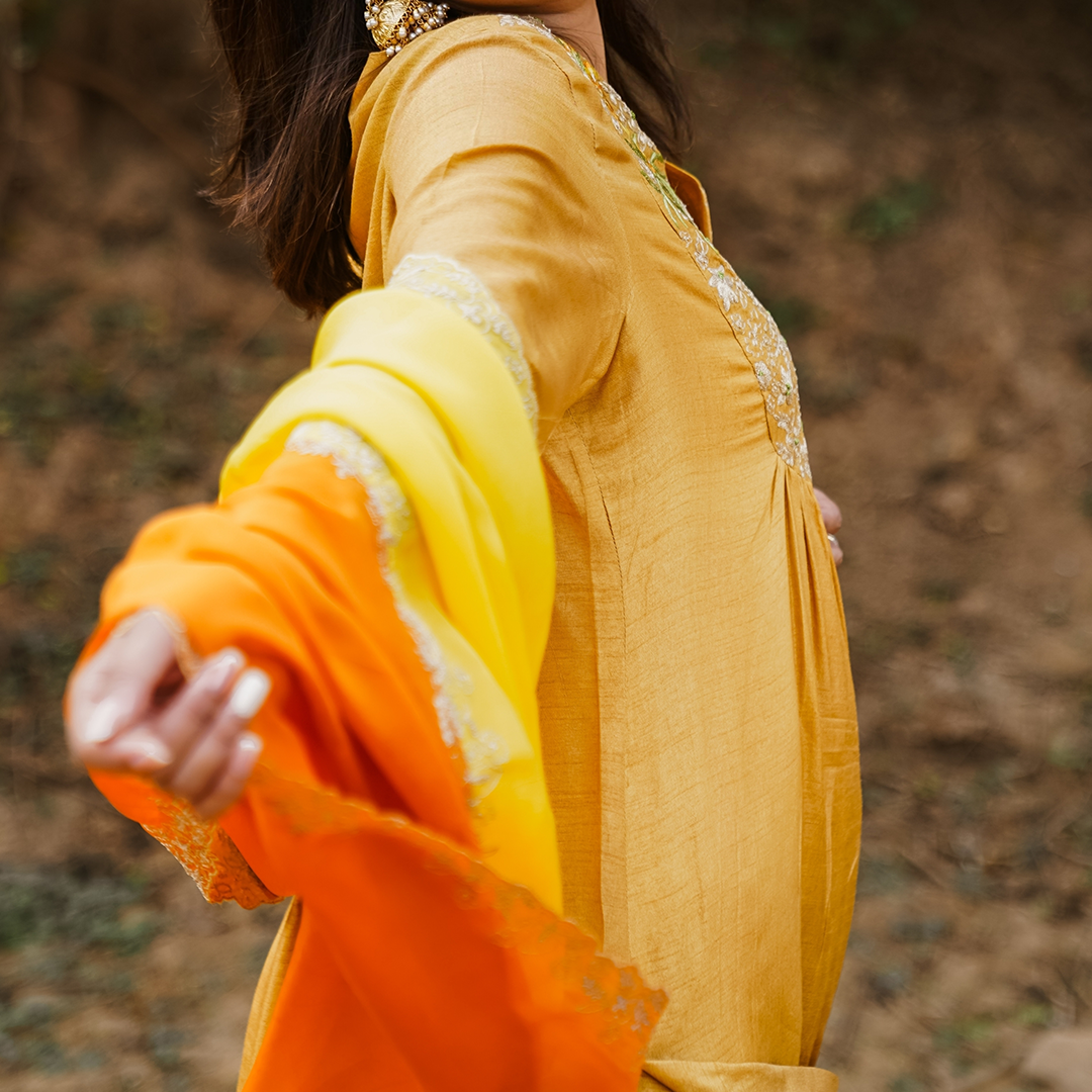 A woman wearing mustard colored Silk Kurta Set with Organza Dupatta.