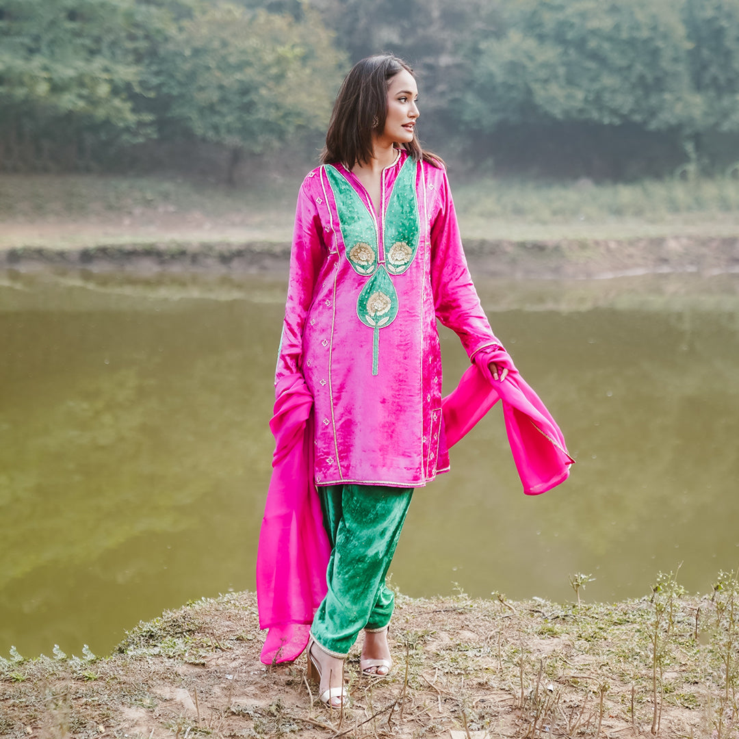 A women wearing pink and green colored Kurta Set with Dupatta.