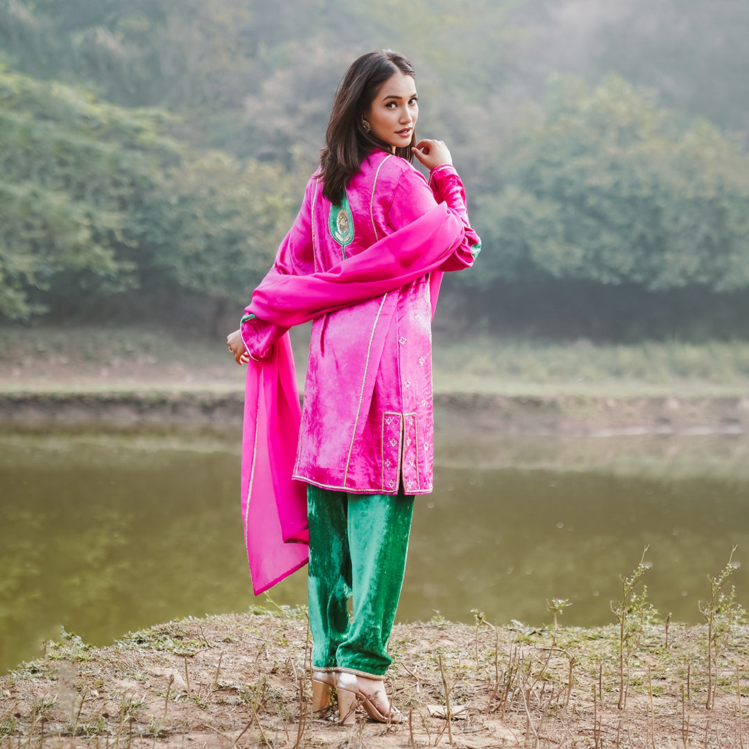 A women wearing pink and green colored Kurta Set with Dupatta.