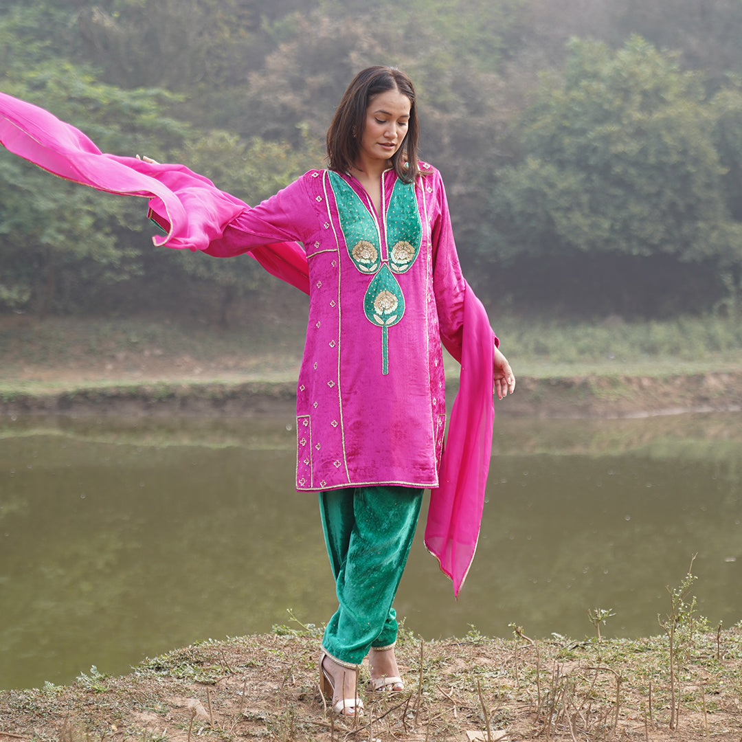 A women wearing pink and green colored Kurta Set with Dupatta.