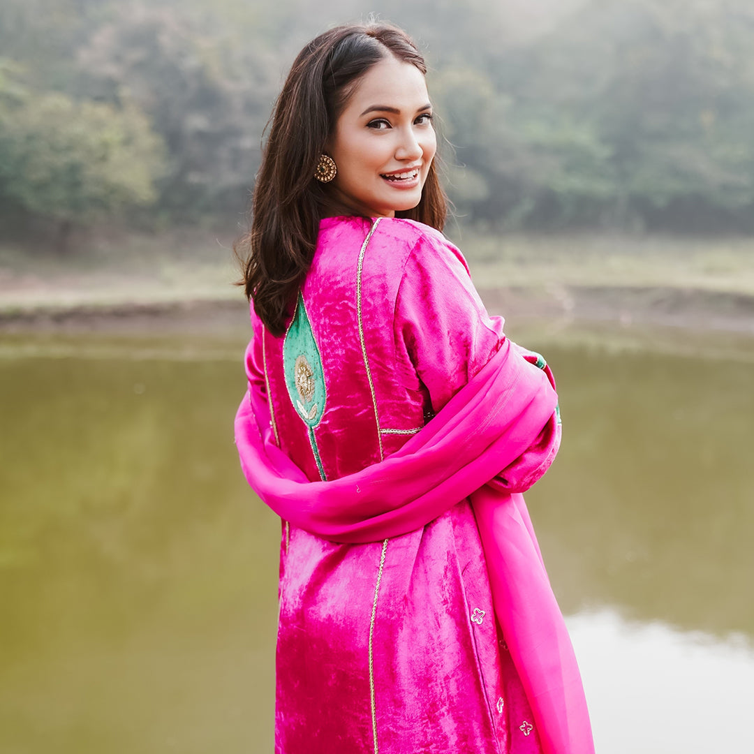 A women wearing pink and green colored Kurta Set with Dupatta.