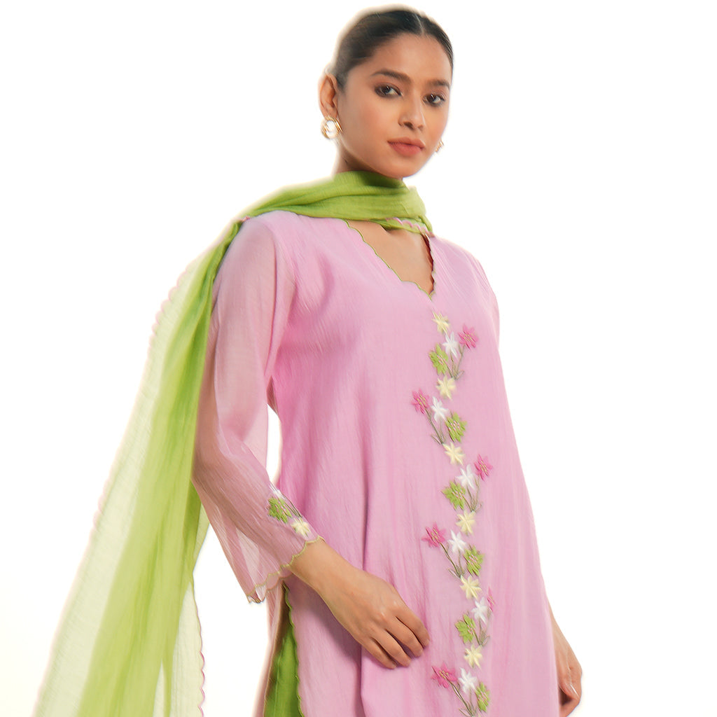 A women wearing light pink colored kurta set with green colored pants with green dupatta.