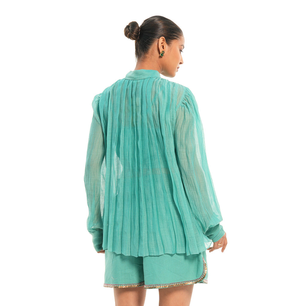 A women wearing full sleeves aqua colored shirt with shorts.