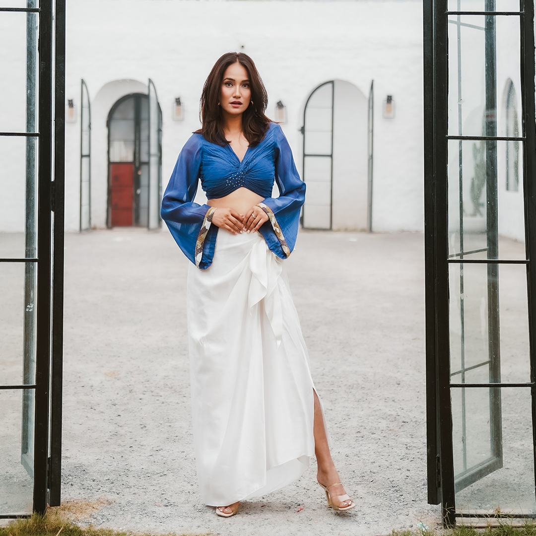 A woman wearing Blue Colored Blouse and White Drape Skirt Co-ord Set.