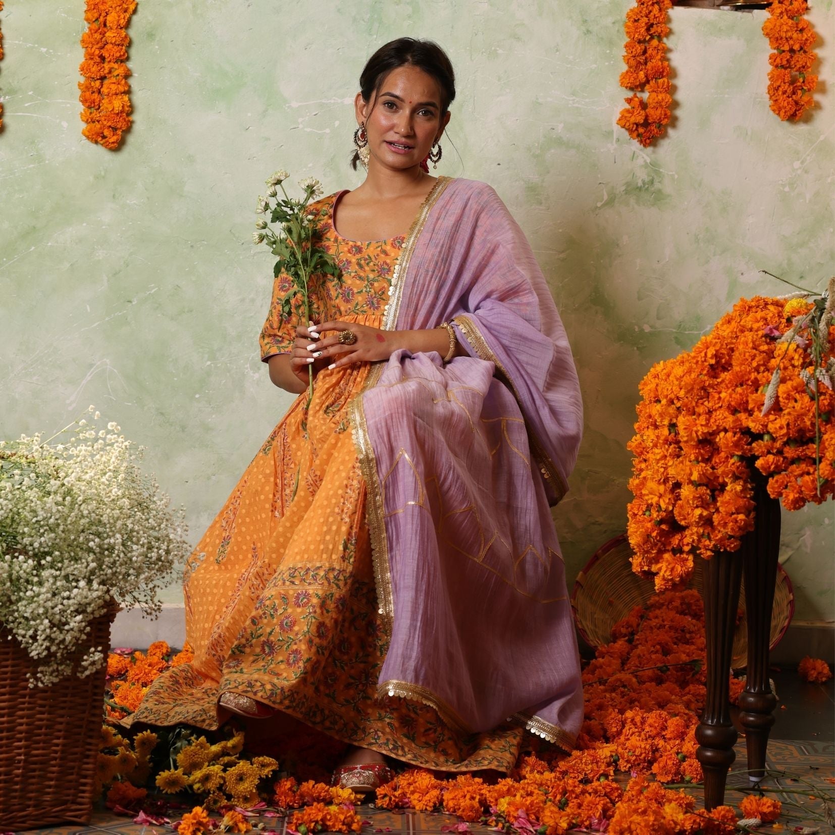 A women wearing Orange Anarkali Kurta Set with Purple Dupatta.