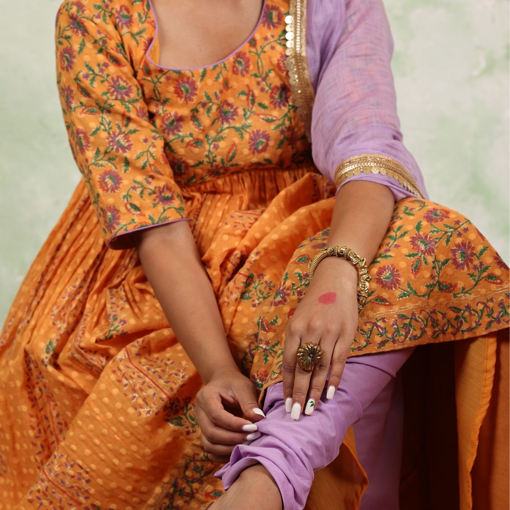 A women wearing Orange Anarkali Kurta Set with Purple Dupatta.