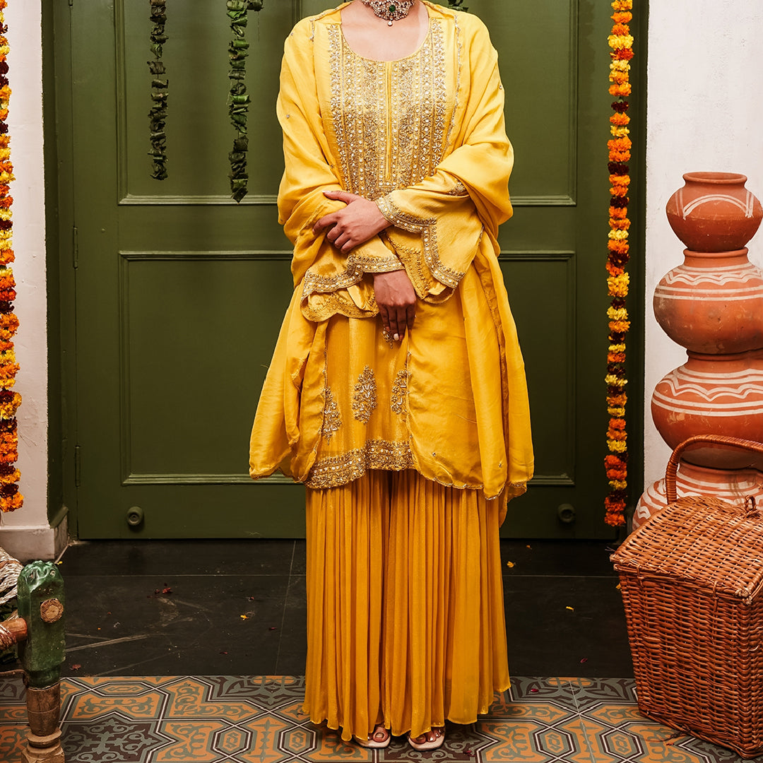 A woman wearing Yellow Sharara Suit set with Dupatta.