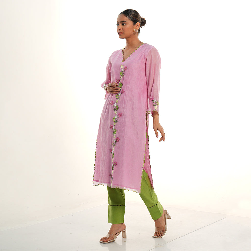 A women wearing light pink colored kurta set with green colored pants.