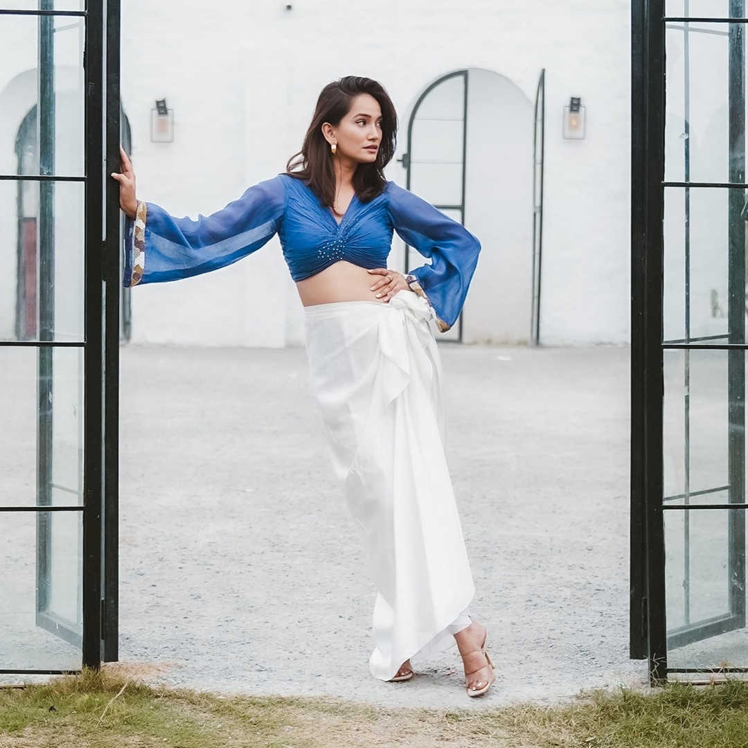 A woman wearing Blue Colored Blouse and White Drape Skirt Co-ord Set.