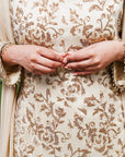 A women wearing beige colored Sharara Suit Set with Dupatta.