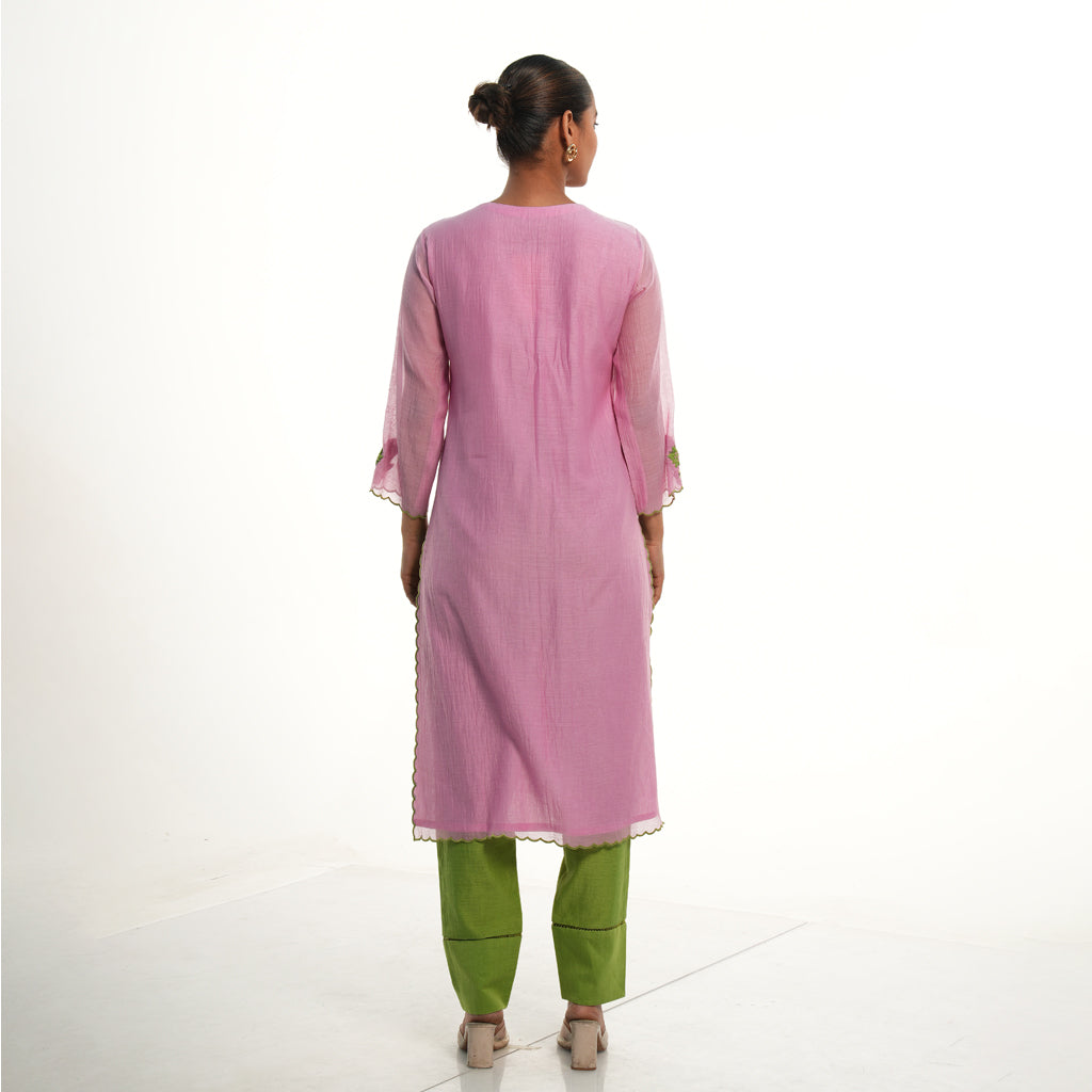 A women wearing light pink colored kurta set with green colored pants.