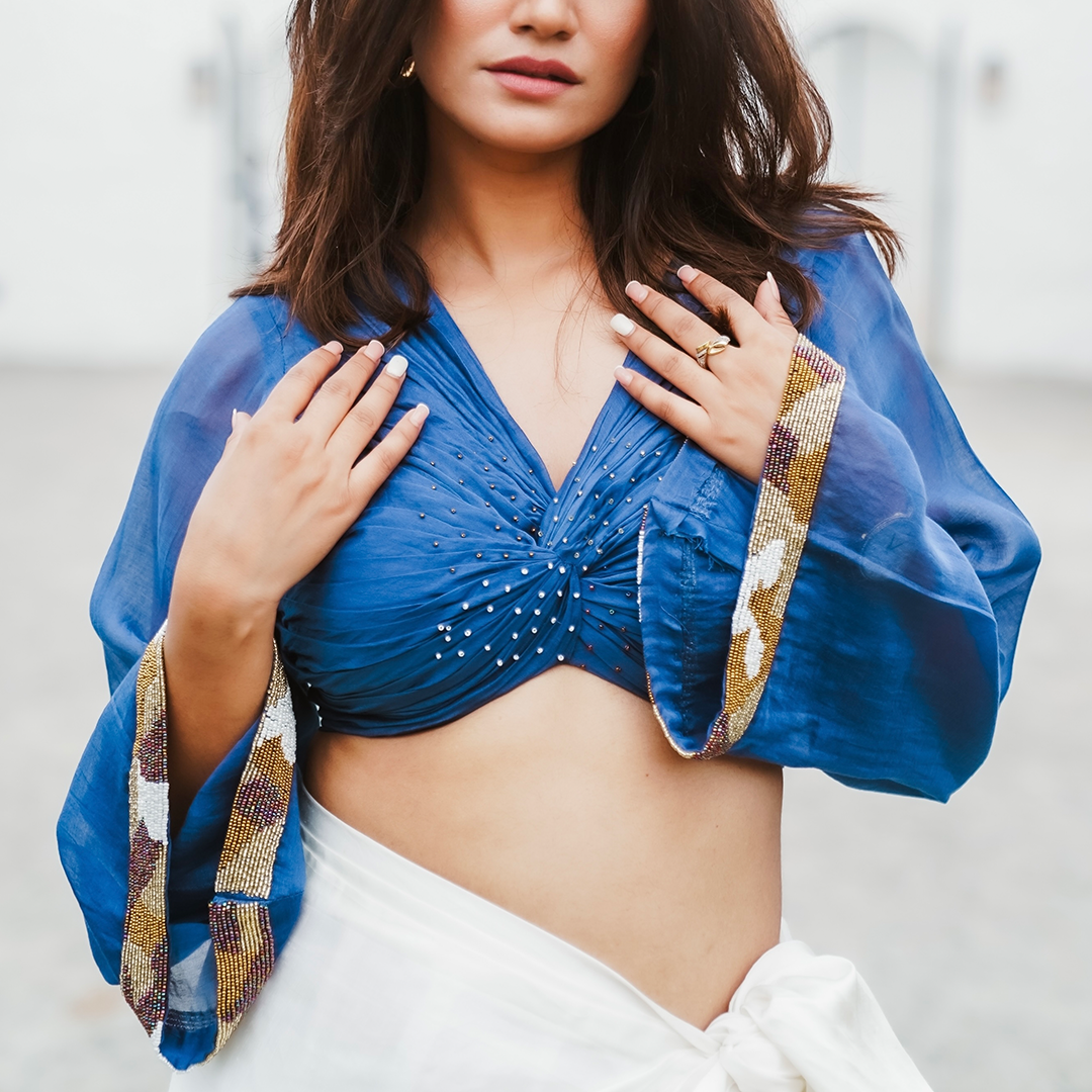 A woman wearing Blue Colored Blouse and White Drape Skirt Co-ord Set.