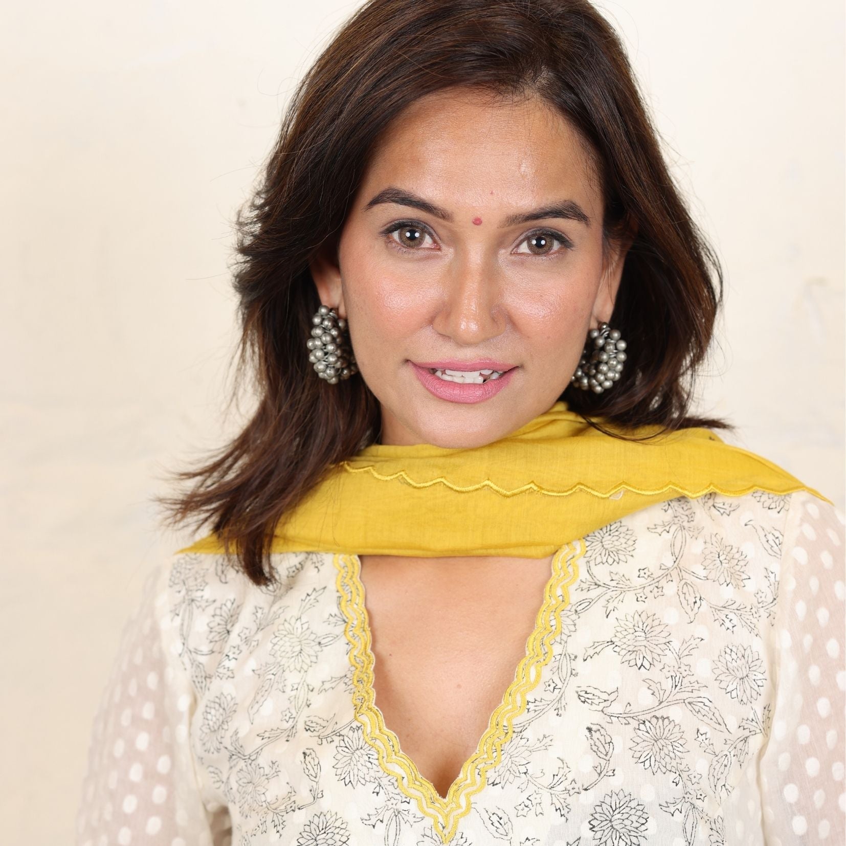 A women wearing white and yellow kurta set with Dupatta.