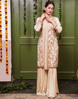 A women wearing beige colored Sharara Suit Set with Dupatta.