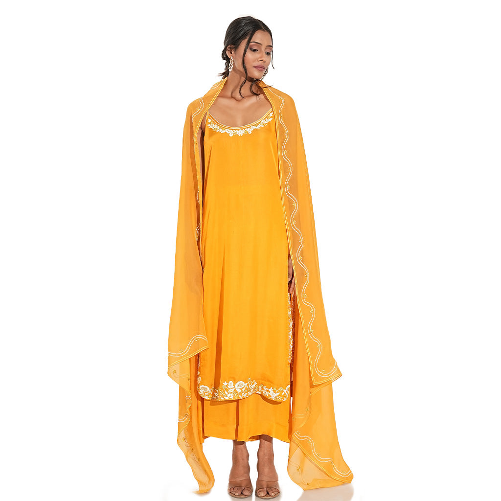 A women wearing stylish whole orange kurta set with palazzo and dupatta.