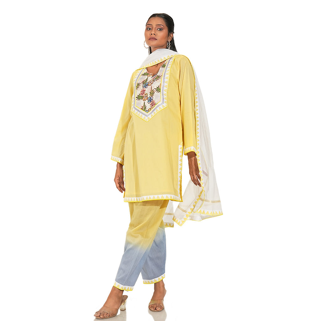 A women wearing yellow colored kurta set with yellow and blue pants with white dupatta.