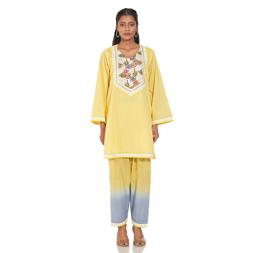 A women wearing yellow colored kurta set with yellow and blue pants.