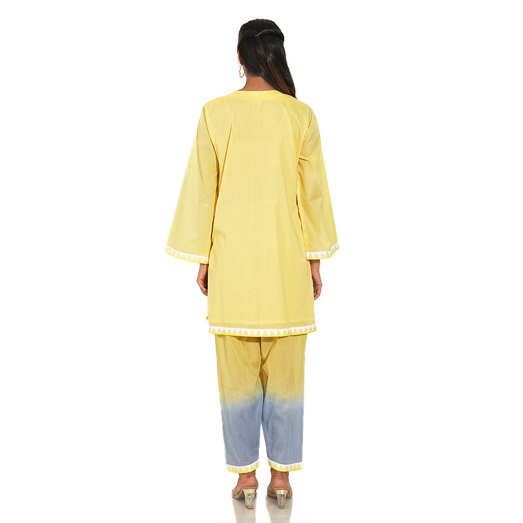 A women wearing yellow colored kurta set with yellow and blue pants.