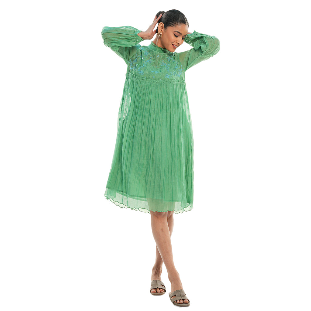 A women wearing green colored full sleeves designer dress with knee length.