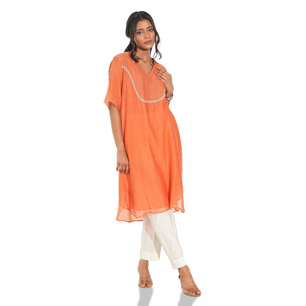 A women wearing Orange Kurta Set with White Pants.