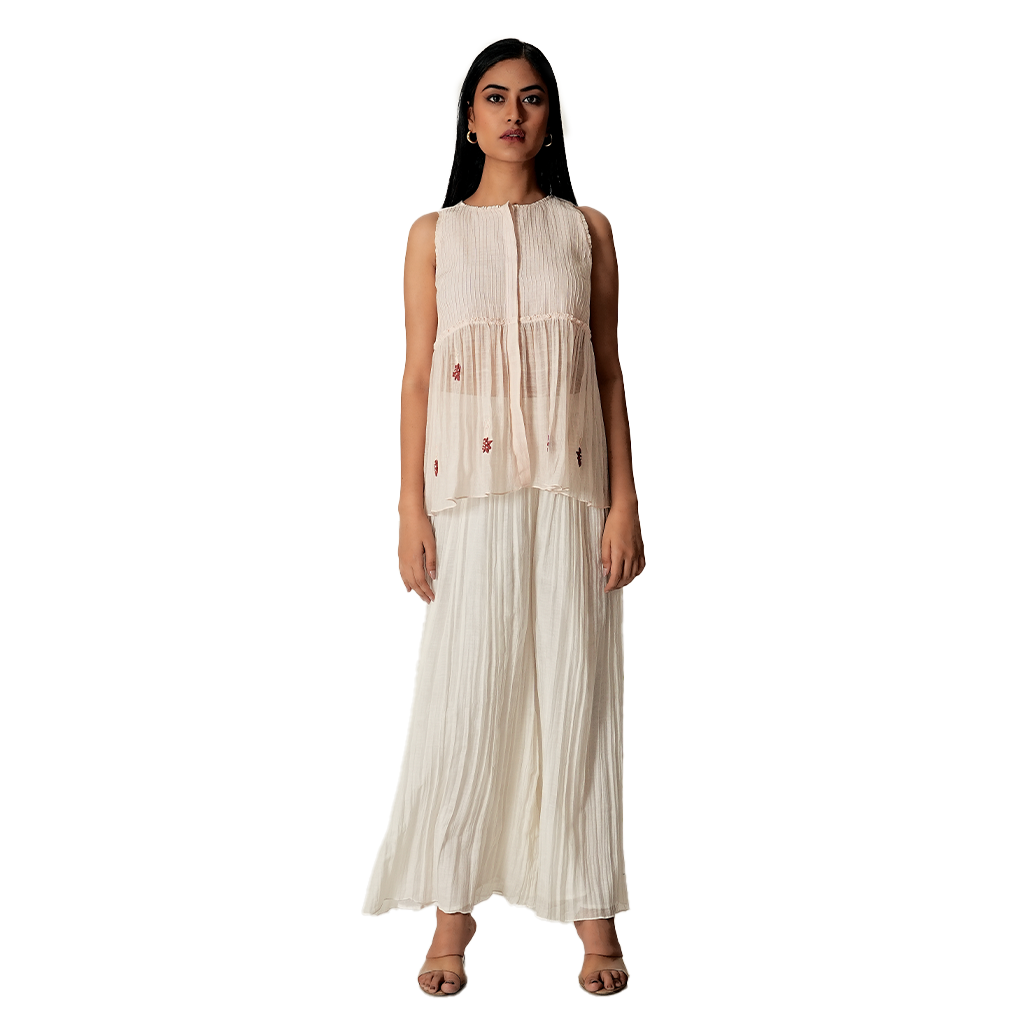 A women wearing pink salt colored designer sleeveless top with palazzo.