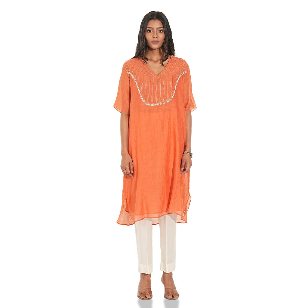 A women wearing Orange Kurta Set with White Pants.